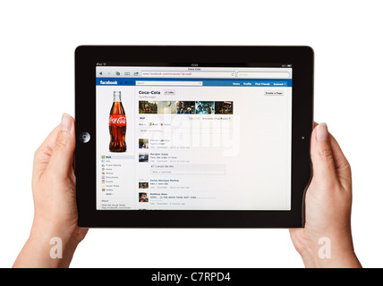 Female hands holding iPad showing online Coca Cola Facebook page Stock Photo