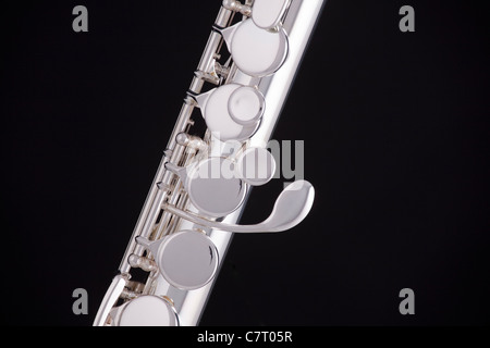 A professional silver alto flute woodwind instrument isolated against a black background. Stock Photo