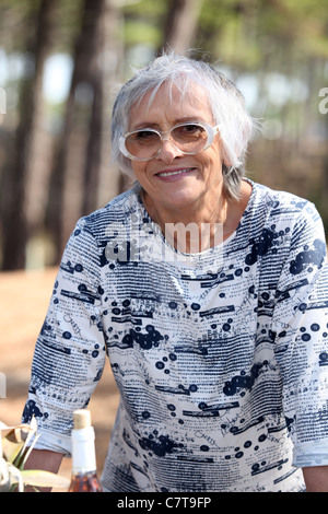 Older woman outdoors with a bottle of wine Stock Photo