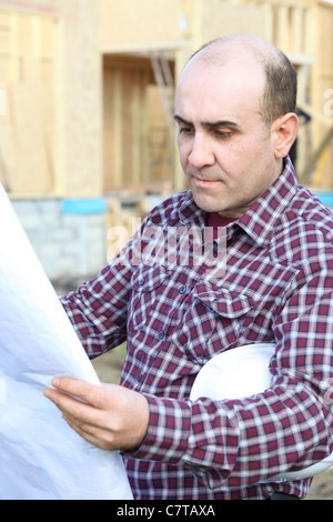 Housebuilder looking at plans on site Stock Photo