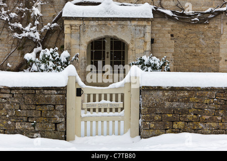 Detail of a snow covered gate and front door on Silver Street House, a cotswold village house in the South Cerney, Gloucestershi Stock Photo