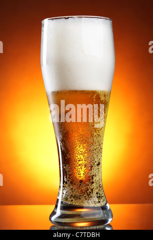 Glass of beer with froth over yellow background Stock Photo