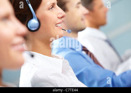 Female operator answering a call among her colleagues Stock Photo