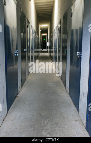 view down a corridor in a self storage unit with padlocked doors on either side Stock Photo