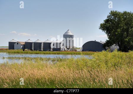 A prairie landscape shot showing grain storage bins and recent flooding to farmland in Saskatchewan, Canada. Stock Photo