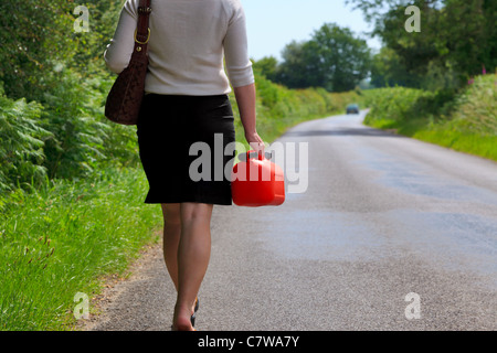 Photo of a woman who's vehicle has broken down walking along a country lane with a spare fuel can in her hand. Stock Photo