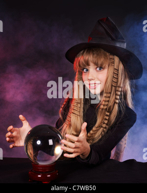 Little girl witch holding crystal ball. Stock Photo