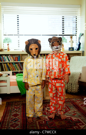 Two kids with masks on in pajamas Stock Photo