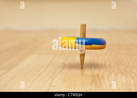 Colorful traditional wooden spinning top spinning on a wooden surface Stock Photo