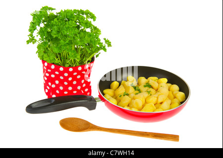 Frying new potatoes in red pan with fresh parsley Stock Photo