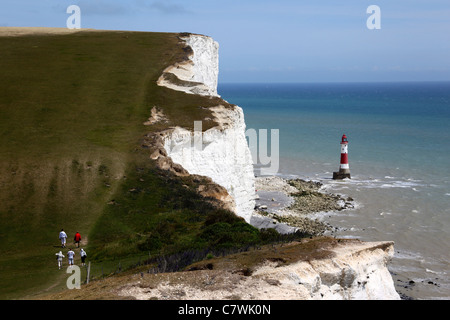 Hikers walking along South Downs Way coast path, Beachy Head lighthouse in background , near Eastbourne, East Sussex , England Stock Photo
