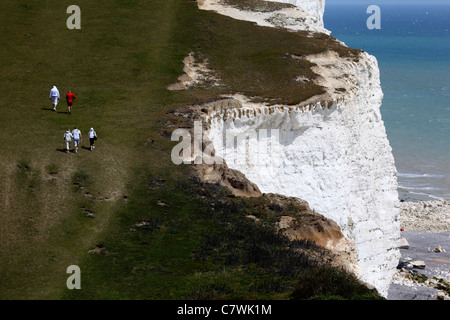 Hikers walking along South Downs Way coast path close to white chalk cliffs, near Eastbourne, East Sussex , England Stock Photo