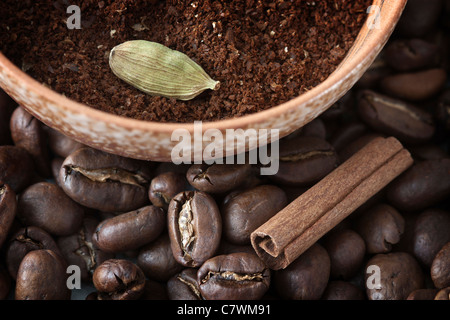 Full frame image of coffee beans and powdered coffee with cinnamon and cardamom, the ingredients for Indian coffee. Stock Photo
