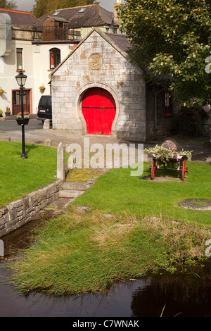 Ireland, Co Wicklow, Aughrim, Horseshoe shaped archway with red painted door to old forge beside the river Stock Photo