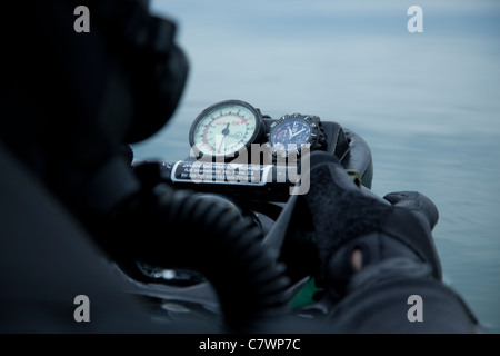 Special operations forces combat diver checks the depth gauge on his compass. Stock Photo