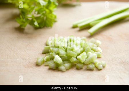 celery stalks on wooden board with celery leaves and chopped celery backlit Stock Photo