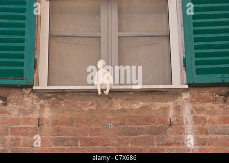 A pottery sculpture of a man sits on a window ledge in Castiglione del Lago, Umbria, Italy. Stock Photo