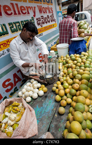 Indian man selling fresh orange juice from a cart on an village street. Puttaparthi, Andhra Pradesh, India Stock Photo