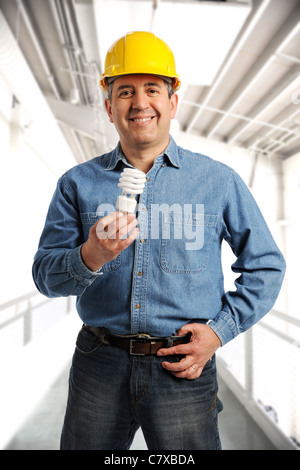 Engineer holding an electrical bulb and wearing a hard hat inside a building Stock Photo