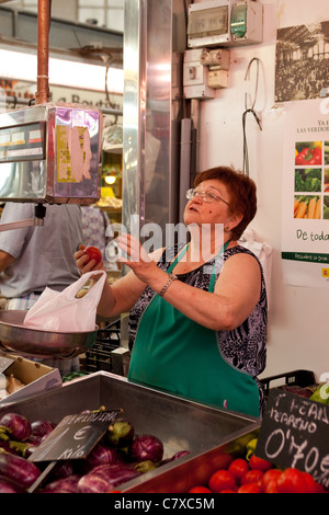 Stall holder weighing fresh vegetables on scales, for customer. Fresh fruit and vegetables for sale at the Mercado Central Valencia Spain Stock Photo