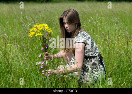 Attractive young caucasian woman picking wildflowers in meadow on summers day in Bristol, England, uk Stock Photo
