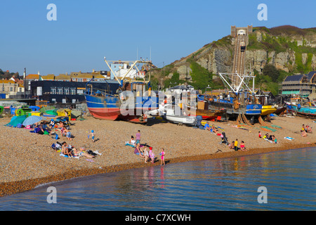 October sunshine, sunbathers and fishing boats in front of the Hastings Contemporary Art Gallery on the Stade beach, at Hastings East Sussex UK Stock Photo