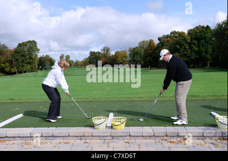 Two golfers at address position on a driving range. Stock Photo