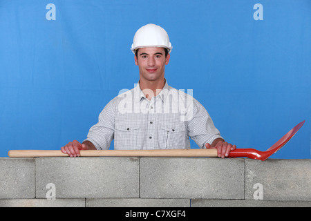 Tradesman's spade laying on a low wall Stock Photo