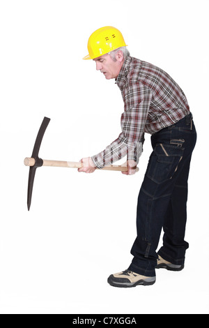 A mature construction worker using a pickaxe. Stock Photo