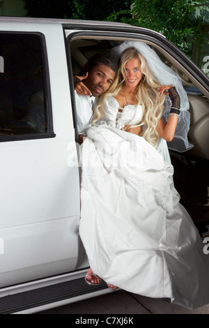 Young Caucasian happy woman in white gorgeous wedding gown sitting in car Stock Photo
