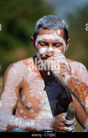 Australian Aborigine man wearing face / body paint and playing the didgeridoo (male Koori didgeriodoo player) Stock Photo