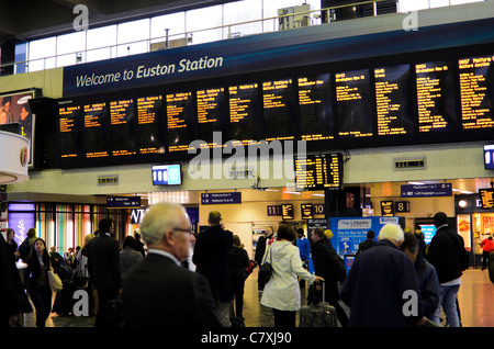 Passengers check departure times in the concourse of Euston Station, London, England. Stock Photo