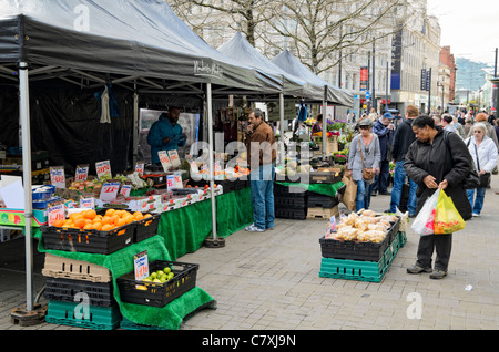 Outdoor market stalls in Piccadilly Gardens, Manchester, England. Customers represent the wide ethnic diversity of the city. Stock Photo