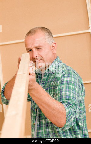 Handyman mature carpenter measures wooden beam for new home improvement Stock Photo