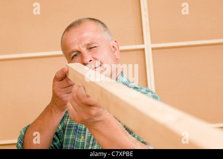 Handyman mature carpenter measures wooden beam for new home improvement Stock Photo