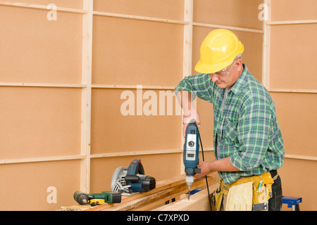 Handyman mature home improvement drilling wood Stock Photo
