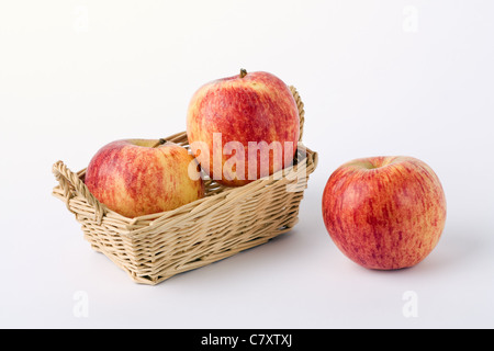 two fresh red apples in wicker basket and one apple isolated on white background Stock Photo