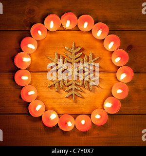 christmas candles circle over wood and golden snowflake symbol Stock Photo