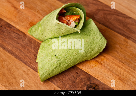 Buffalo chicken wrap in spinach tortilla on wooden surface Stock Photo