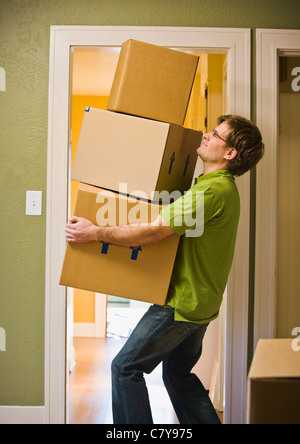 A man carrying three boxes through a doorway. Stock Photo