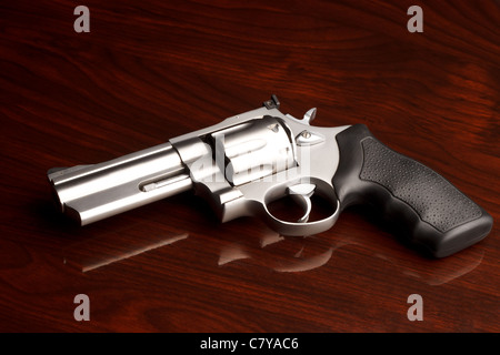 Clean .357 revolver laying on reflective wooden table Stock Photo