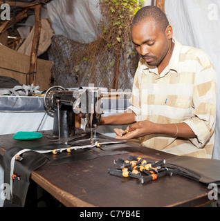 Leather worker stitching handbags with sewing machine in small workshop in Nairobi, Kenya. Stock Photo