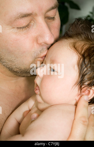 Happy father holds on the hands and kisses his baby Stock Photo