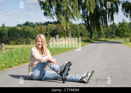 Inline skates young attractive woman wearing jeans sitting asphalt road Stock Photo