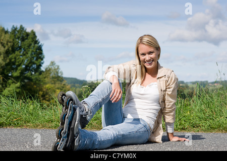 Inline skates young attractive woman wearing jeans sitting asphalt road Stock Photo