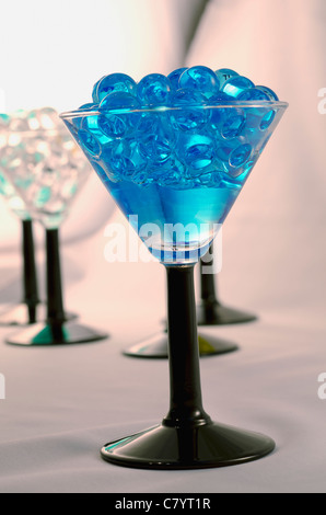 blue marbles in wine glass  with more in the background Stock Photo
