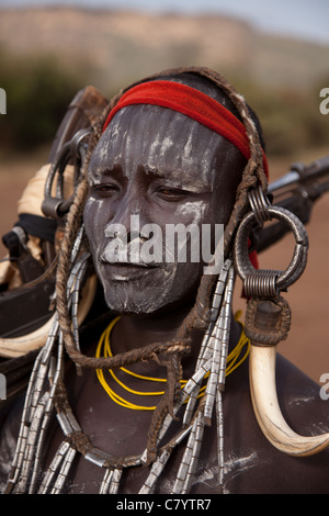Mursi warrior in traditional dress with AK47 guns,  Jinka, Omo Valley, Ethiopia, Africa Stock Photo