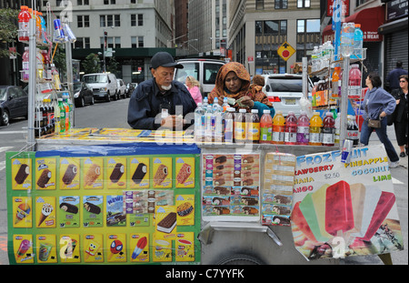 An Indian couple selling ice cream and cold beverages from a food cart on Water Street in Manhattan. Oct. 2, 2011 Stock Photo