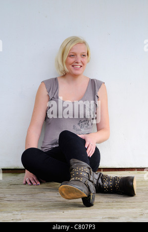 Young woman relaxing outside sitting on a wooden deck. Stock Photo