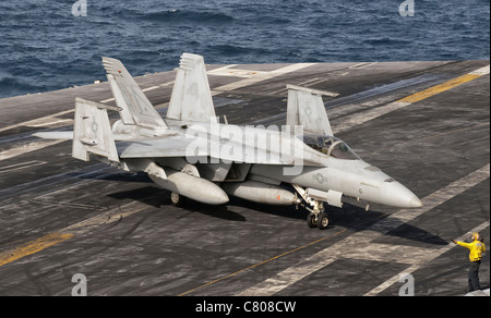 An aircraft director guides an F/A-18F Super Hornet of the US Navy aboard aircraft carrier USS Nimitz. Stock Photo